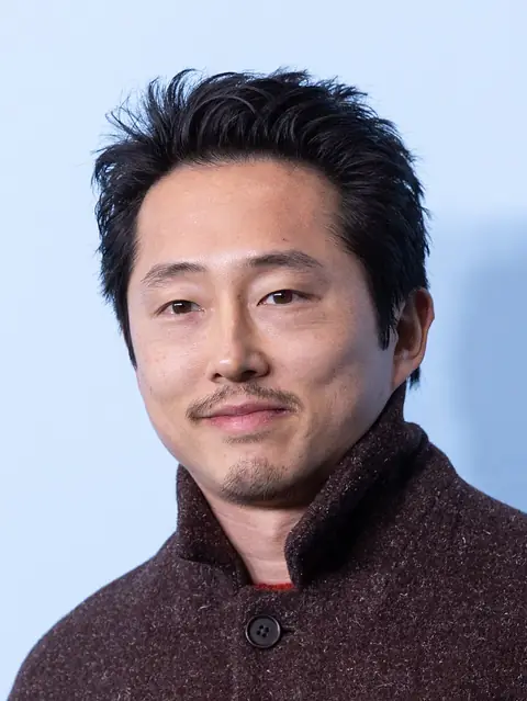 Yeun smiling towards the camera