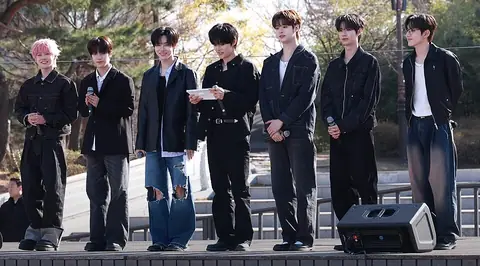 The seven members of Close Your Eyes standing on an outdoor stage