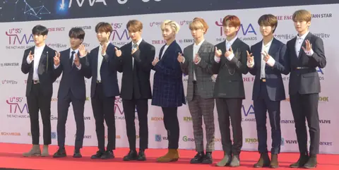 Members of Stray Kids wearing suits on a red carpet.