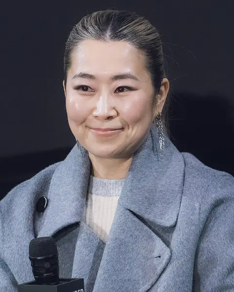 Maggie Kang directly facing the camera while seated