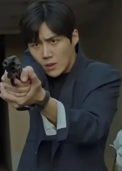 Kim Seon-ho in a navy suit, holding and pointing a firearm in character as detective Go Ji-seok for Catch the Ghost